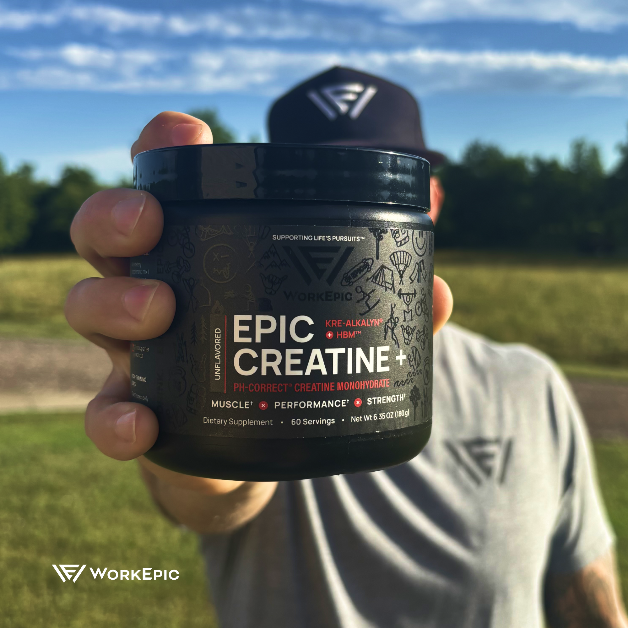 Person holding a container of Epic Creatine+ supplement with a blurred outdoor background