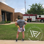 A woman wearing a grey Work Epic shirt by a fire truck