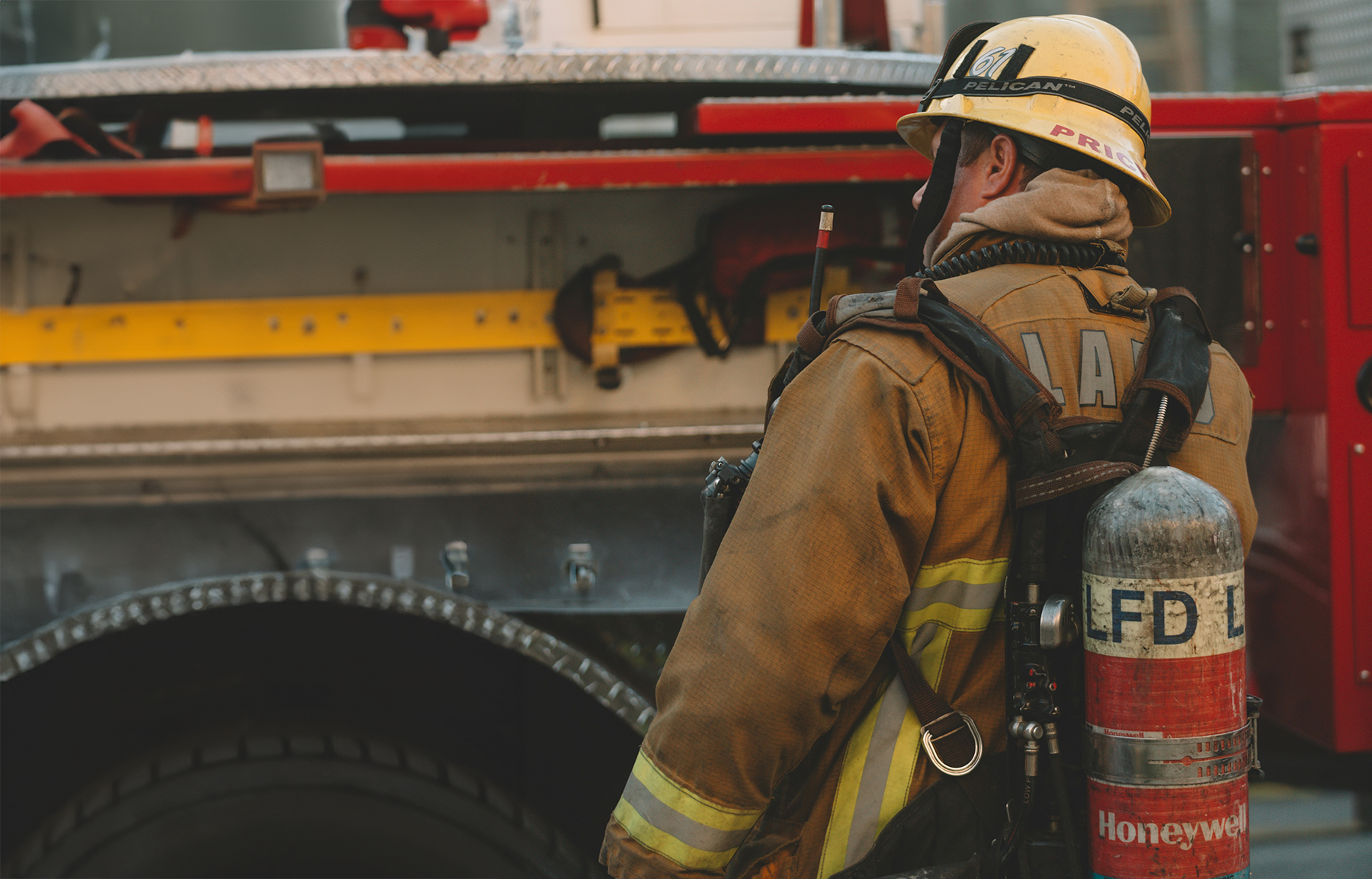 A firefighter next to a fire truck in protective gear